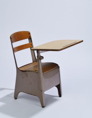 A wooden school desk with attached table and metal legs.