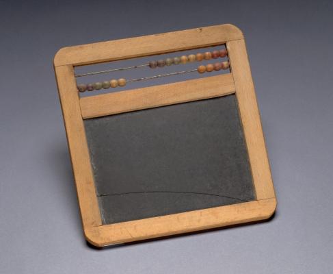 A wooden abacus/slate combo sits on a plain gray background.