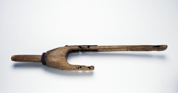 Homemade wooden peg leg laying horizontally on a light backgground.