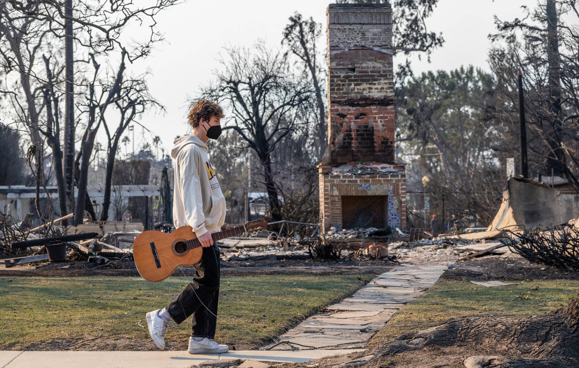 Jet Gross, 17, walks with a guitar that a friend asked to find in Pacific Palisades, CA on Friday, Jan. 10, 2025. (Myung J. Chun / Los Angeles Times via Getty Images)