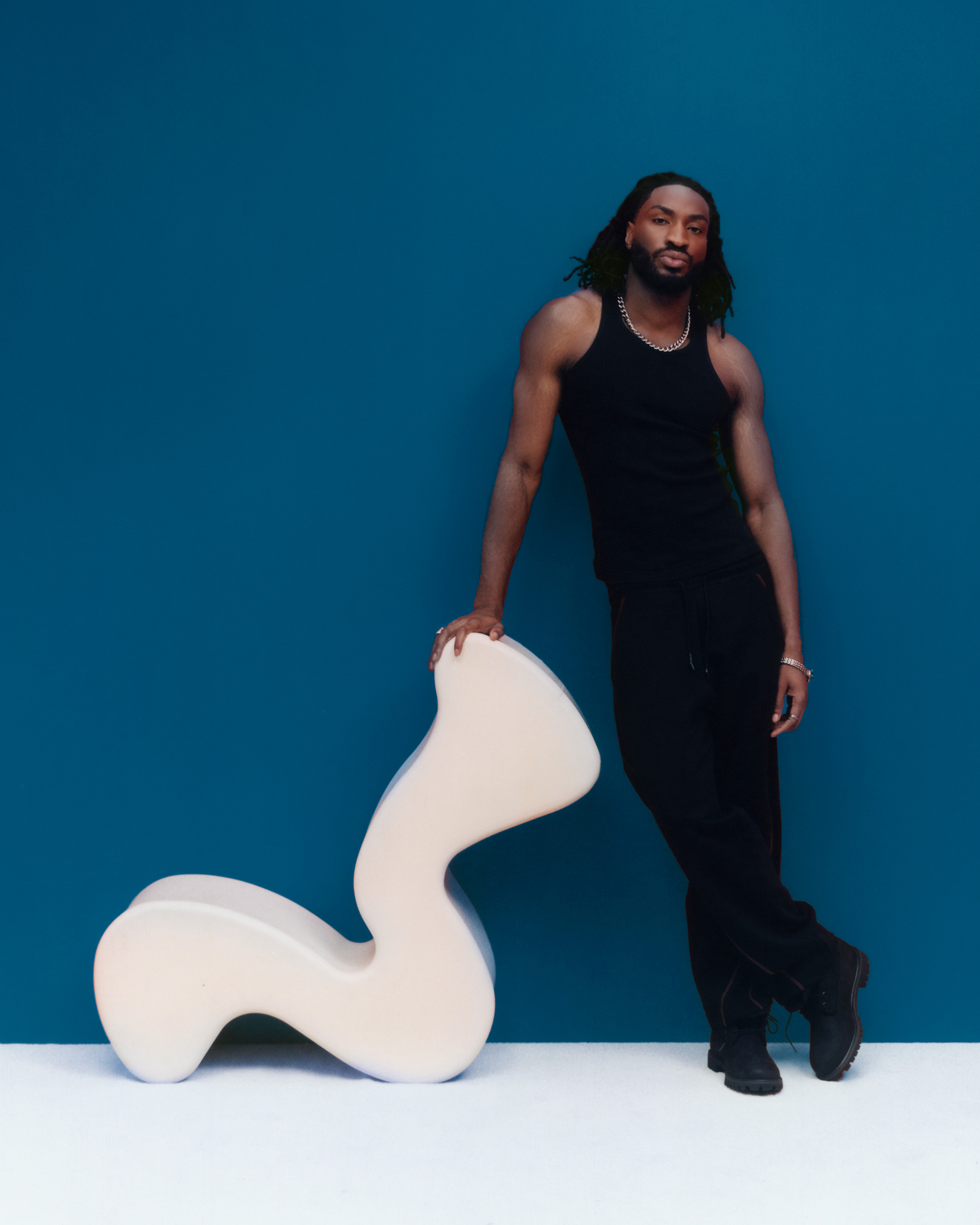 Odeal standing against a wavy white chair, photo by Elliot Hensford