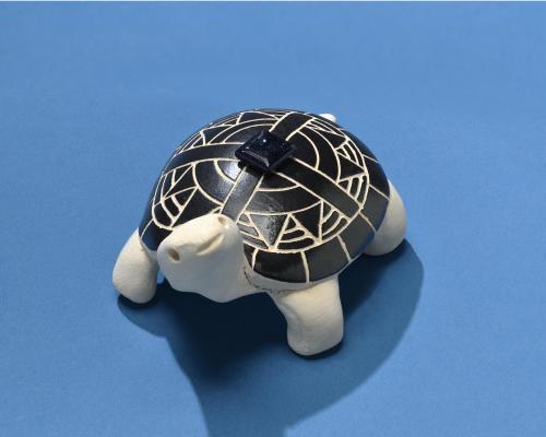 Clay turtle sculpture, with a black shell and symbolic oak leaf