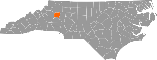 A gray map of North Carolina with Alexander County filled in with orange.